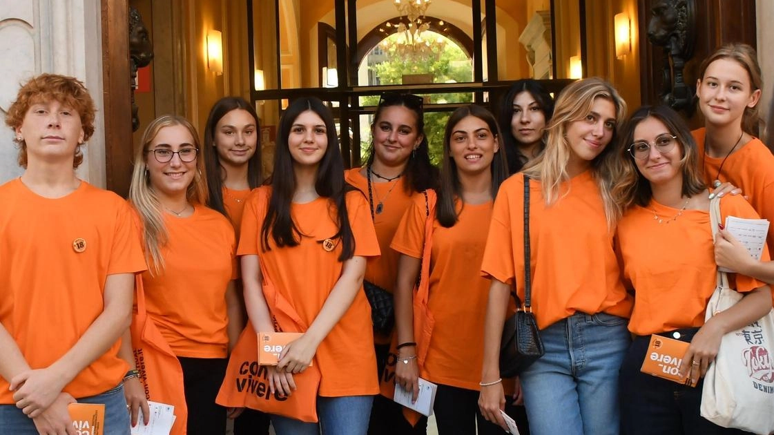 I ragazzi con le magliette arancioni adetti all’accoglienza dei cittadini. e degli ospiti che vogliono orientarsi negli incontri di Con-Vivere I ragazzi con le magliette arancioni adetti all’accoglienza dei cittadini. e degli ospiti che vogliono orientarsi negli incontri di Con-Vivere