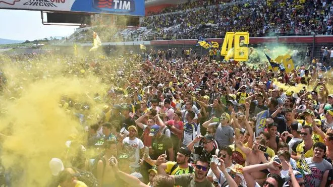 Fans of Italy's Valentino Rossi hold up his number and flares letting off yellow smoke during the podium ceremony of the Italian motorcycling Grand Prix at Mugello racetrack on May 31, 2015. Spain's Jorge Lorenzo won the race ahead of Italy's Andrea Iannone who came in second and Italy's Valentino Rossi who came in third. AFP PHOTO / GABRIEL BOUYS