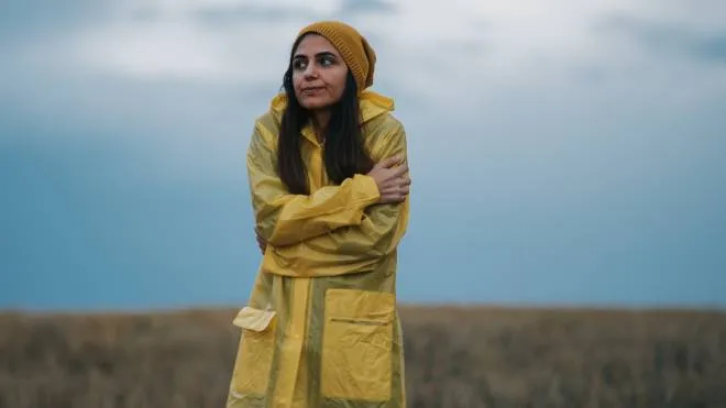 Young girl wearing a yellow raincoat in rainy and cold day