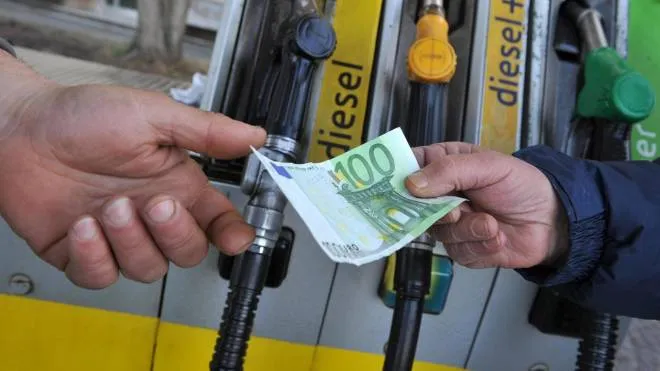 Un benzinaio alla pompa di benzina, riceve un biglietto da 100 euro per il pagamento del carburante da un cliente. ANSA/FRANCO SILVI
