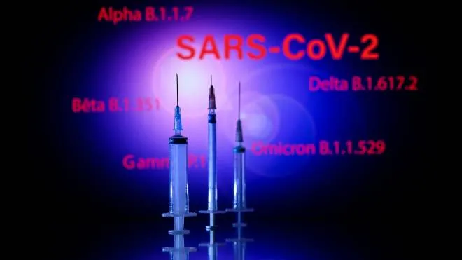 This photograph taken on December 2, 2021, shows a syringe and a screen displaying the SARS-Cov-2 mains variants : Alpha, Beta, Delta, Gamma and Omicron, in Toulouse. (Photo by Lionel BONAVENTURE / AFP)