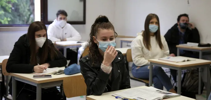 Un gruppo di studenti in classe, tutti con la mascherina ben allacciata