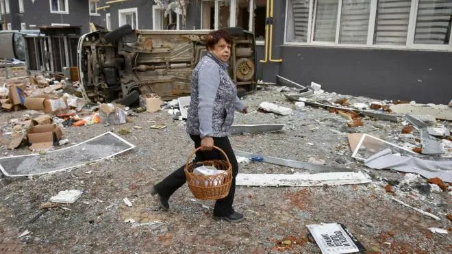 epa09870784 A woman carries food in front of a damaged residential building in Bucha city, which was the recaptured by the Ukrainian army, Kyiv (Kiev) area, Ukraine, 04 April 2022. More than 410 bodies of killed civilians were carried from the recaptured territory in Kyiv's area for exgumation and expert examination. The UN Human Rights Council has decided to launch an investigation into the violations committed after Russia's full-scale invasion of Ukraine as Ukrainian Parliament reported. On 24 February, Russian troops had entered Ukrainian territory in what the Russian president declared a 'special military operation', resulting in fighting and destruction in the country, a huge flow of refugees, and multiple sanctions against Russia.  EPA/OLEG PETRASYUK ATTENTION: GRAPHIC CONTENT