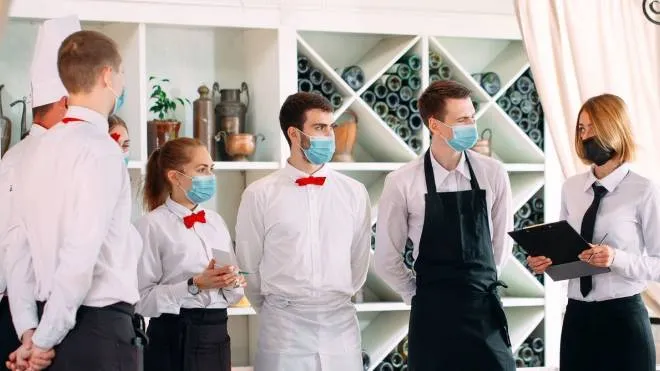 Lucidi Istockphoto - Employees of a Restaurant or Hotel in protective masks. End Of Quarantine. Restaurant Manager and his staff on the terrace. interaction with the chef in the restaurant