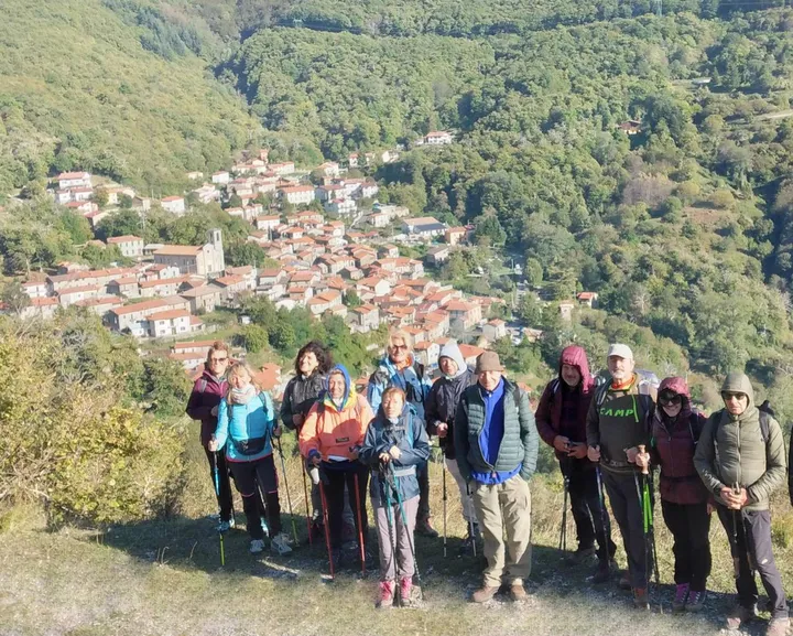 Escursionisti con alle spalle il borgo di Sassalbo