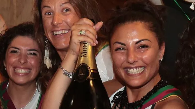 Sopra Laura Rosi sorride con la bottiglia che le ha regalato il Drago A destra è in Piazza a prendere il cavallo