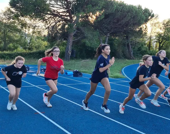 Giovani atlete mentre si allenano usando la pista di atletica a Quercia