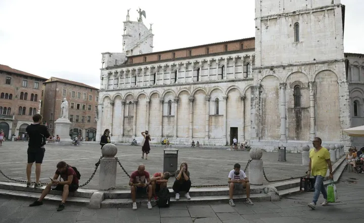 Turisti e passanti seduti sugli scalini del sagrato di piazza San Michele (foto Alcide)