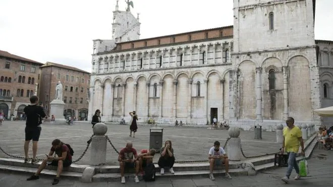 Turisti e passanti seduti sugli scalini del sagrato di piazza San Michele (foto Alcide)