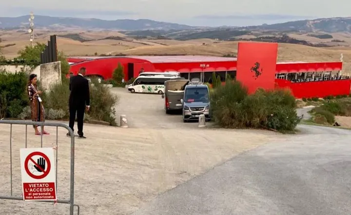 Sopra il nuovo suv Ferrari che sfreccia sulle strade di Lajatico; sotto il Teatro del Silenzio tinto di rosso