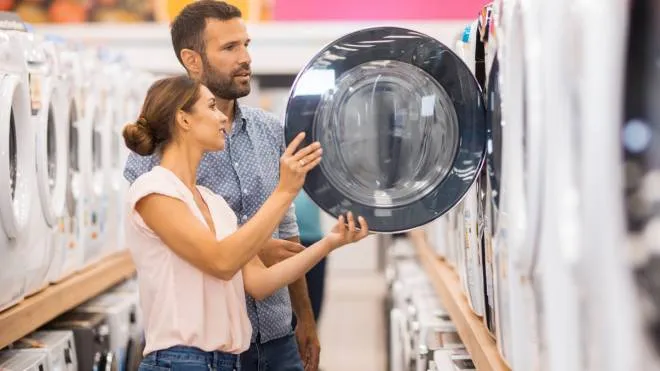 Young couple seen in a home appliances store in front of a drying machine.