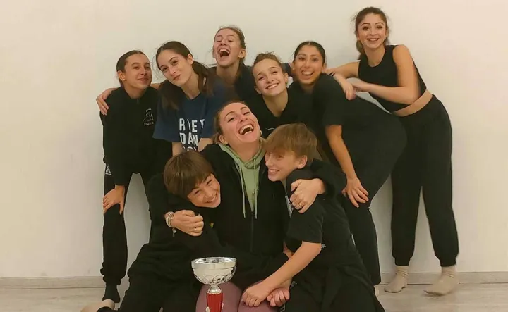L’insegnante di danza Giulia Barnini sorridente insieme ai suoi allievi con la coppa