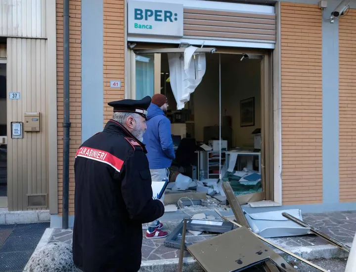 I carabinieri davanti alla porta sventrata della filiale Bper: il bancomat è stato sradicato in piena notte