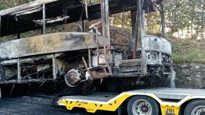 La carcassa dell’autobus bruciato viene portata via (foto Borghesi)