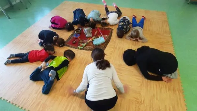 Un gruppo di bambini fa yoga insieme alle insegnanti Alice Pocai e Daniela Bigagli
